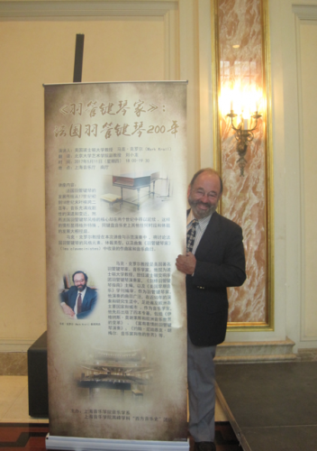 Mark Kroll stands before a poster for his recital in Shanghai.