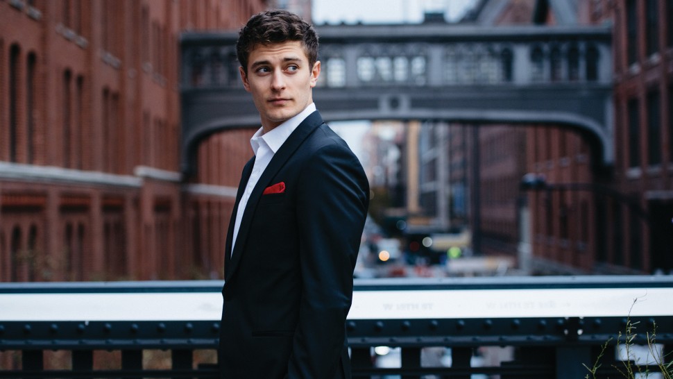 Jakub Józef Orliński standing outdoors on a walkway above traffic.