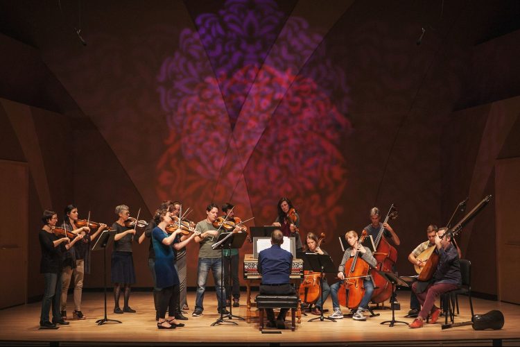 Orchestra members perform on a stage.