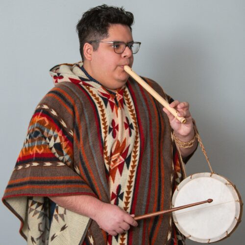 Christoper Ellis Montes in a traditional Peruvian ponco plays the pipe and tabor.
